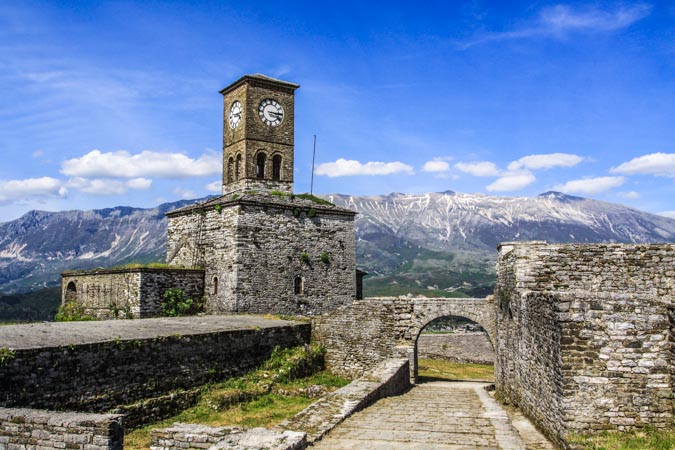 Albania, Gjirokastër, sitio Patrimonio Mundial UNESCO: Castillo con torre del reloj y arco. Montañas al fondo