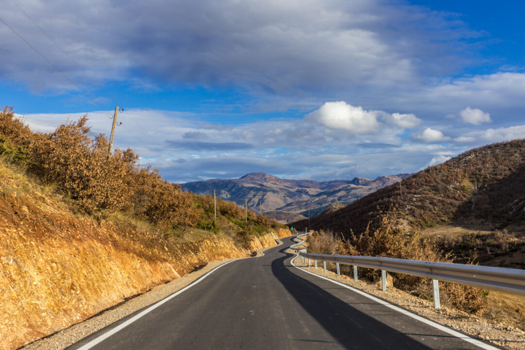 secondary road in countryside with blue sky with clouds in Korçë county, Albania