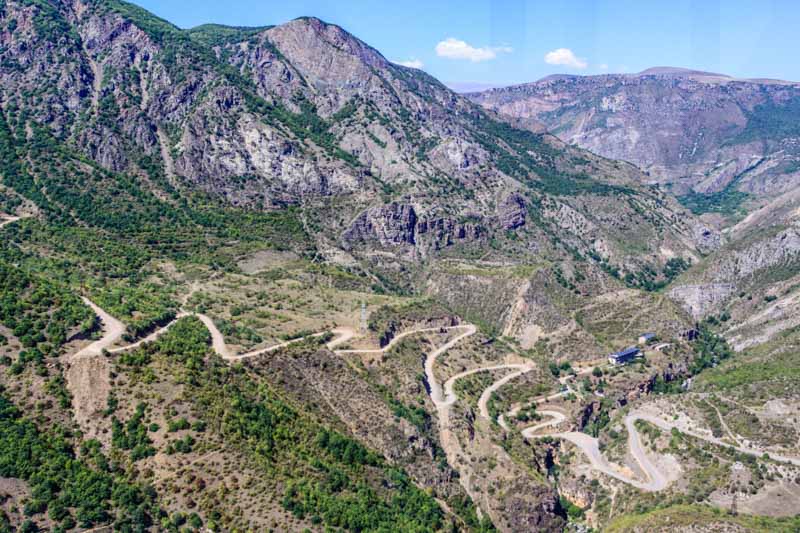 Tatev, Armenia: winding mountain road and green patches. View of the Vorotan river gorge from Wings of Tatev cable car