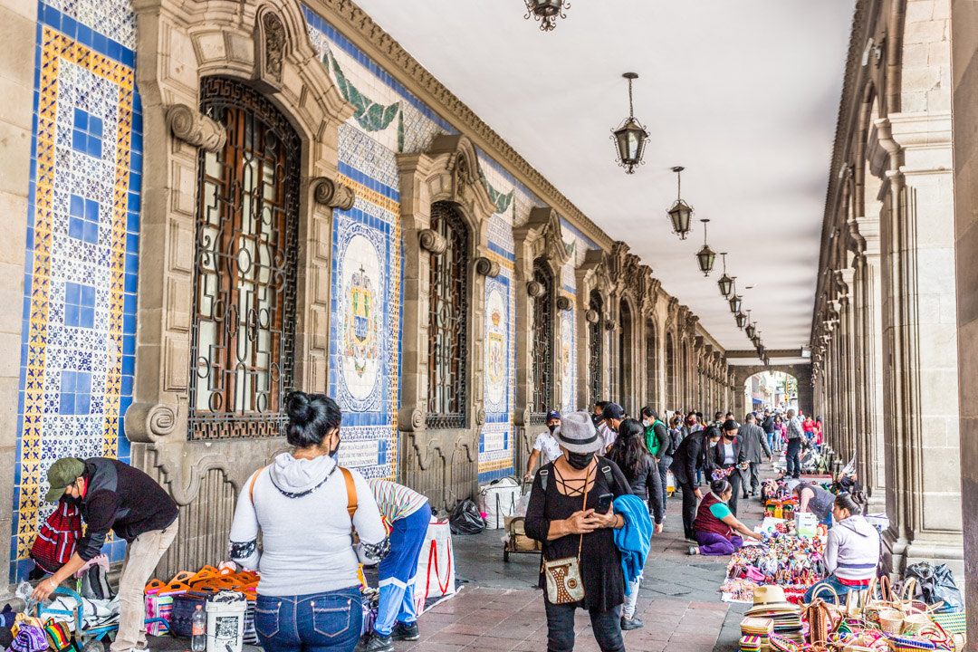 Ciudad de México. Zócalo: soportales del antiguo ayuntamiento con vendedores ambulantes y decoración de azulejos