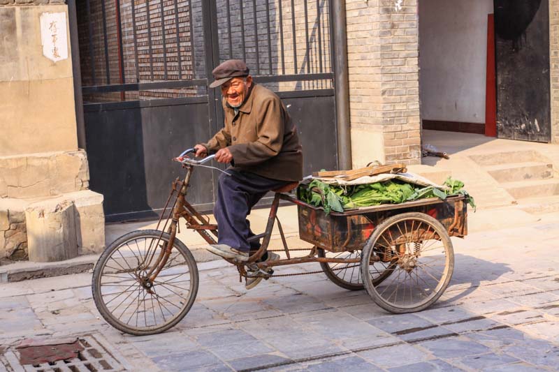 An old man carrying vegetables by bicycle in Pingyao old town (Shanxi Province, China)