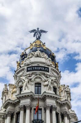 Famous neoclassical building in Madrid in white stone with statues and dome topped with angel.