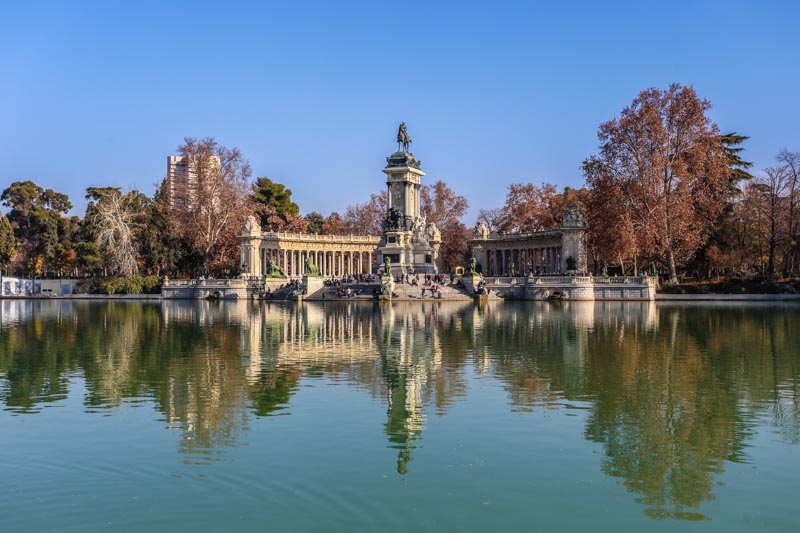 Monument with columns behind artificial lake in central park, Retiro Gardens, in Madrid