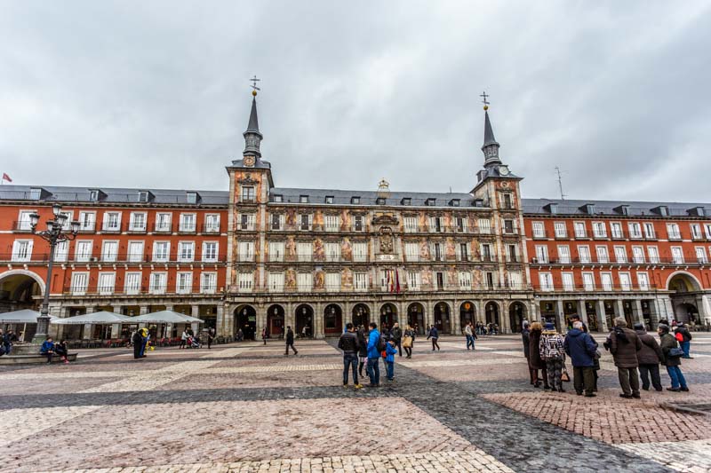Historical main market square in Madrid old city, plaza mayor. Red building with frescoes and blue slate roofs